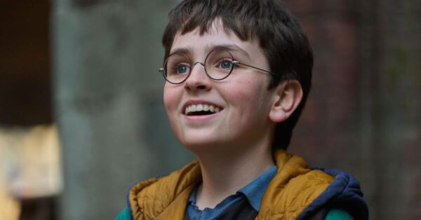 Dominic McLaughlin jako Harry Potter v seriálu HBO - chlapec s kulatými brýlemi se usmívá a dívá vzhůru