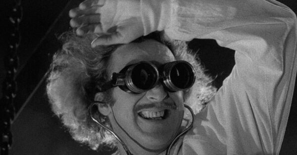 Gene Wilder jako Dr. Frederick Frankenstein s ochranými brýlemi a nadšeným výrazem ve filmu Young Frankenstein