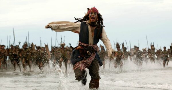 Johnny Depp jako kapitán Jack Sparrow běží po pláži v akční scéně z filmu Piráti z Karibiku: Truhla mrtvého muže