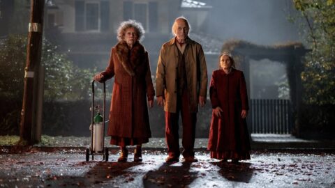 Tři záhadné starší postavy stojí za denního světla před domem ve filmu Insidious: Out of the Further