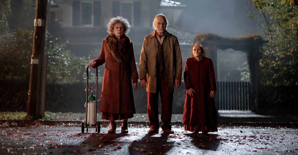 Tři záhadné starší postavy stojí za denního světla před domem ve filmu Insidious: Out of the Further