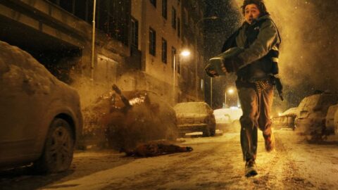 Austin Abrams jako Bryan prchá zasněženou ulicí zachvácenou požárem ve filmu Resident Evil
