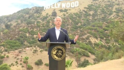 Kalifornský generální prokurátor Rob Bonta hovoří na tiskové konferenci k žalobě proti fúzi Paramountu a Warner Bros., v pozadí nápis Hollywood.