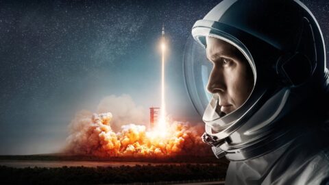 Ryan Gosling jako Neil Armstrong ve skafandru sleduje start rakety Saturn V ve filmu První člověk