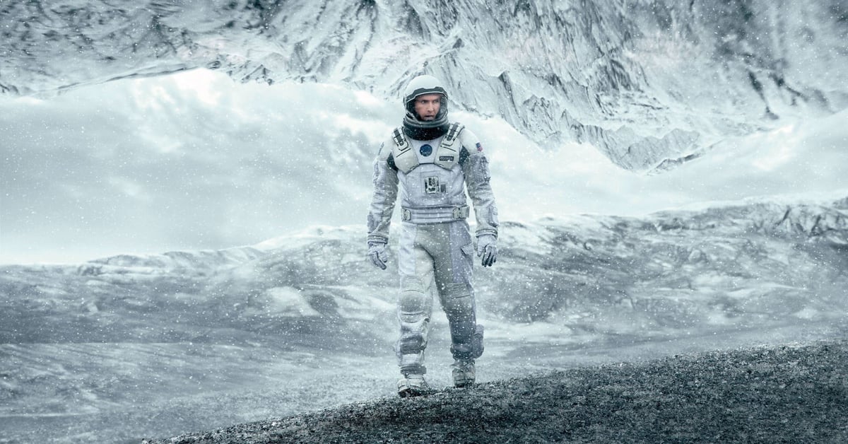 Astronaut v bílém skafandru kráčí po zamrzlé planetě se zasněženými horami v pozadí – záběr z filmu Interstellar