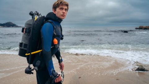 Austin Abrams jako Jay Gardiner v potápěčské výbavě na pláži před natočením scén z filmu Whalefall