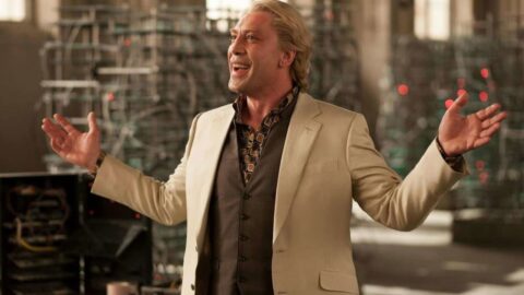 Javier Bardem jako zaporak Silva ve filmu Skyfall, usmivajici se s roztazenyma rukama v osvetlene hale