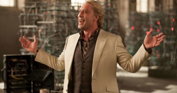 Javier Bardem jako zaporak Silva ve filmu Skyfall, usmivajici se s roztazenyma rukama v osvetlene hale