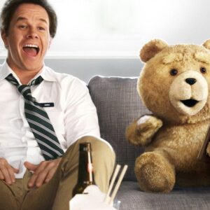 Mark Wahlberg se směje na pohovce vedle medvídka Teda s lahví piva ve filmu Méďa