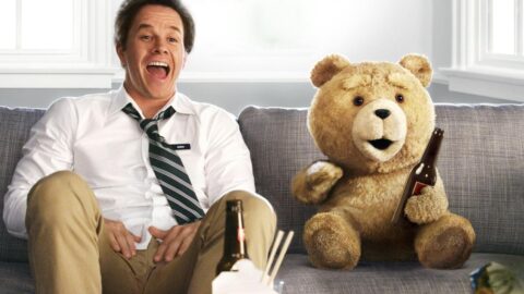 Mark Wahlberg se směje na pohovce vedle medvídka Teda s lahví piva ve filmu Méďa