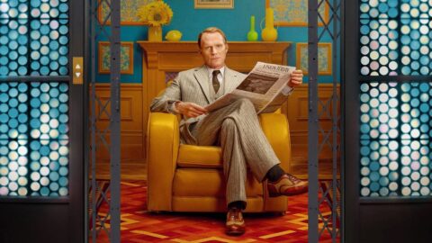 Paul Bettany jako Vision sedí v křesle a čte noviny s titulkem Vision Today v barevném interiéru ze seriálu VisionQuest